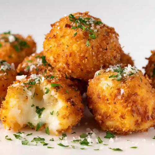 Golden-brown Cheesy Parmesan Mozzarella Bites, arranged in a row on a baking sheet, with a crispy Parmesan crust and a gooey mozzarella inside—perfect for parties and appetizers.