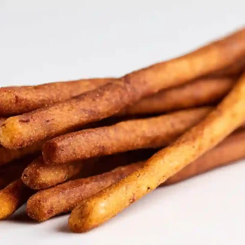 A stack of crispy golden potato finger sticks on a white background, perfect for dipping or snacking.