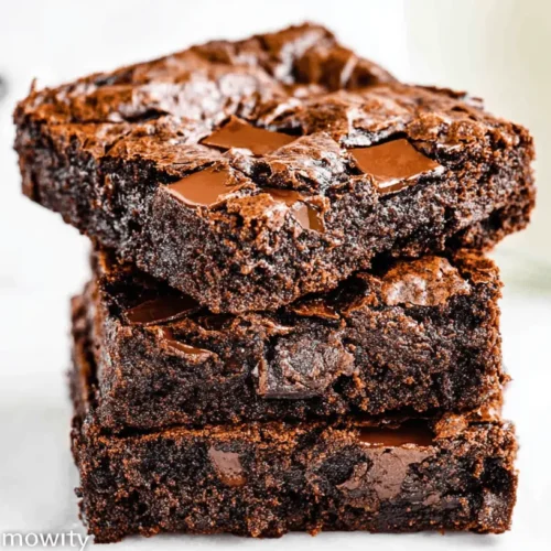 A stack of three rich, fudgy brownies with chocolate chunks and a crinkly top, showcasing the delicious results of an Eggless Brownies Recipe.