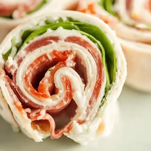 Close-up of vibrant, freshly cut Italian pinwheels revealing layers of deli meats, cream cheese, and lettuce.
