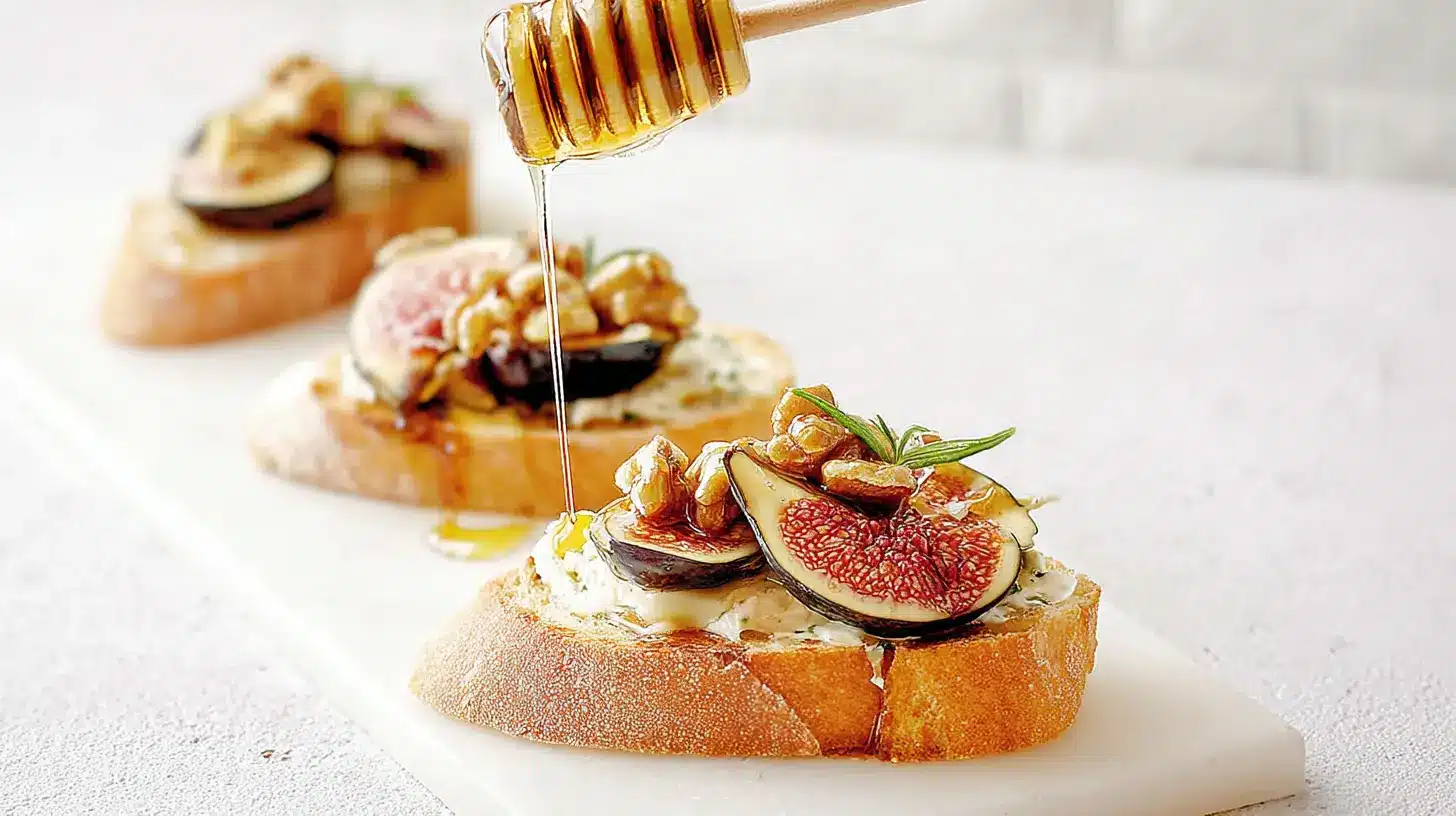 Elegant finger foods: Gourmet fig and walnut crostini drizzled with golden honey on a white board.